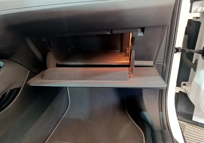 Gros plan sur la boîte à gants ouverte côté passager d'une BMW X2 blanc 2023, intérieur noir.