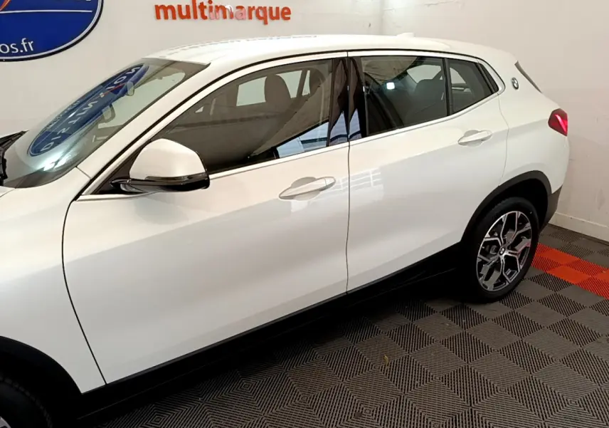 Profil côté gauche d'un BMW X2 blanc 2023 avec jantes alliage et logo BMW sur l'aile arrière