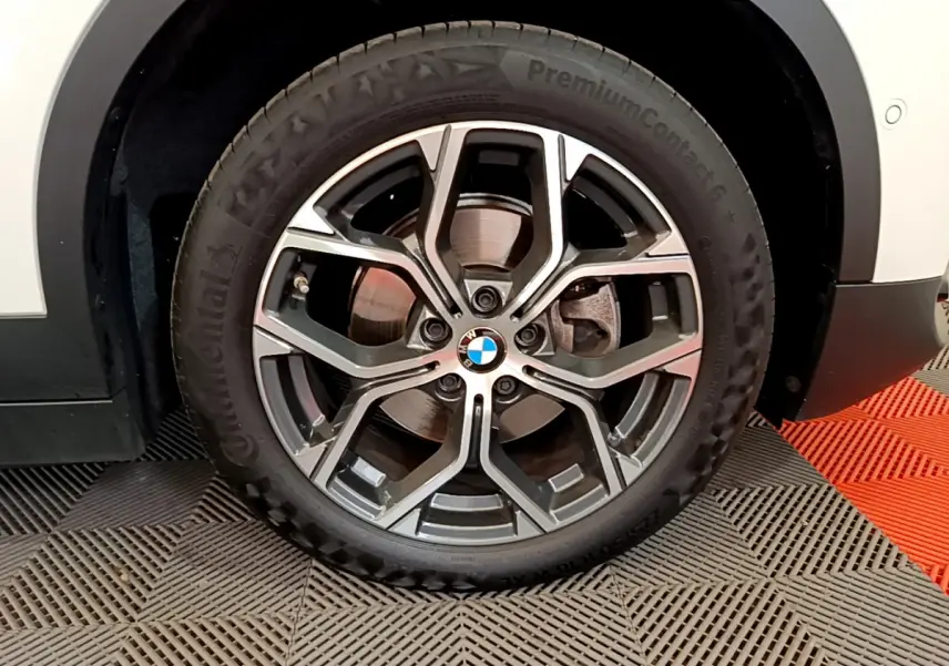 Gros plan sur la roue avant droite avec jante alliage et logo BMW du BMW X2 blanc 2023 sDrive18i Business DesignDKG7.