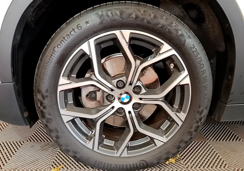 Gros plan sur la jante alliage et pneu Continental d’un BMW X2 blanc, version sDrive18i Business DesignDKG7 2023.