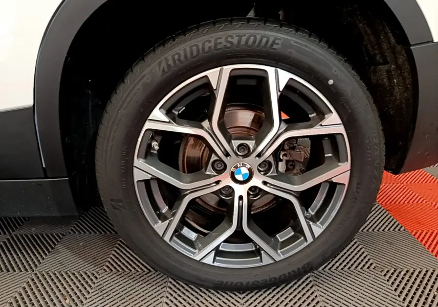Gros plan sur la roue avant droite du BMW X2 blanc, mettant en valeur la jante alliage et le pneu Bridgestone.