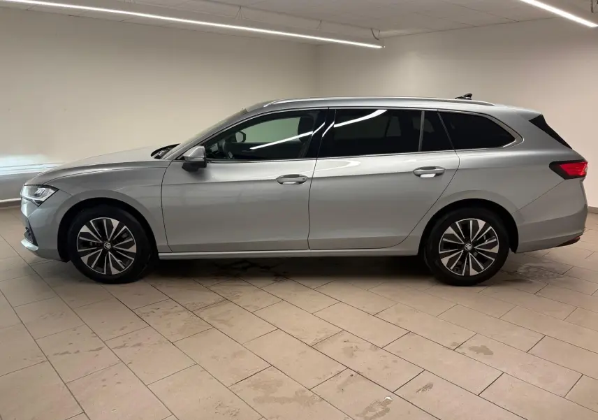 Vue de profil côté gauche d'une Skoda Superb Combi gris argent 2025 avec jantes alliage et vitres teintées.