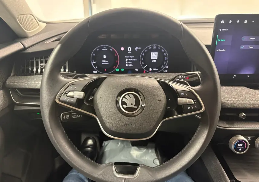 Vue intérieure centrée sur le volant noir de la Skoda Superb Combi 2025 avec tableau de bord numérique et écran tactile.