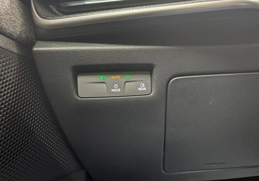 Détail du tableau de bord du Skoda Superb Combi 2025, montrant les commandes d'éclairage automatiques avec indicateurs lumineux verts et orange.