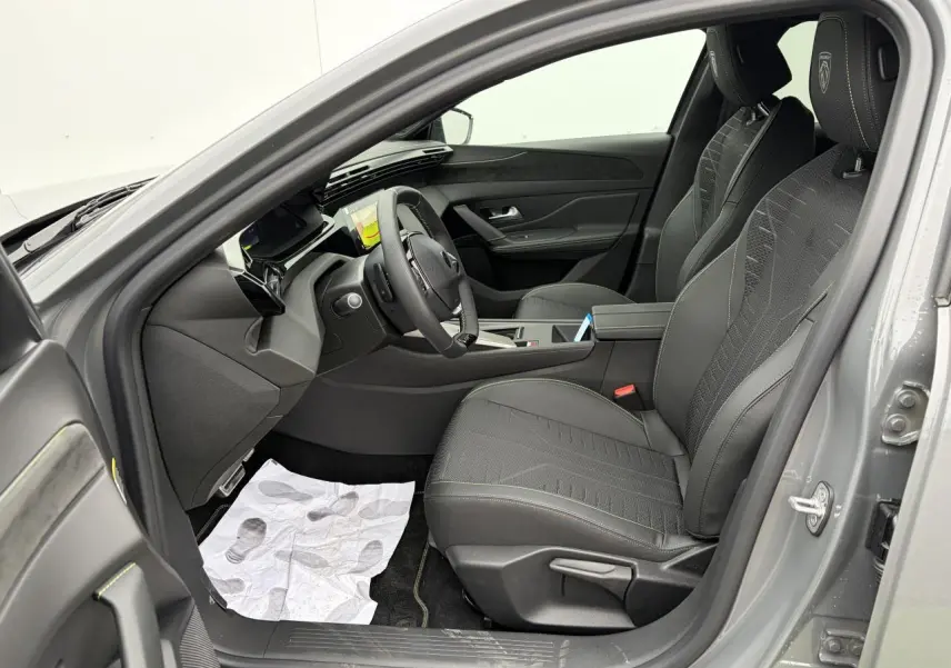 Intérieur côté conducteur de la Peugeot 308 gris selenium, sièges noirs avec surpiqûres vertes et volant compact GT cuir.