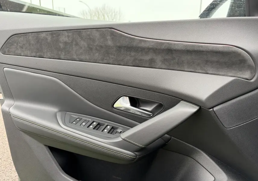 Gros plan sur la porte avant gauche de la Peugeot 308 gris sélénium, avec surpiqûres vert Adamite et insert en alcantara.