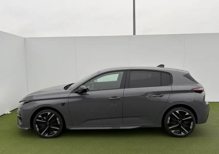 Profil droit d'une Peugeot 308 III hybride 2025 gris selenium avec jantes alliage noires et vitres surteintées.