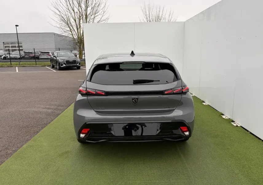 Vue arrière d'une Peugeot 308 III gris sélénium avec feux arrière LED en forme de griffes et vitrage surteinté.