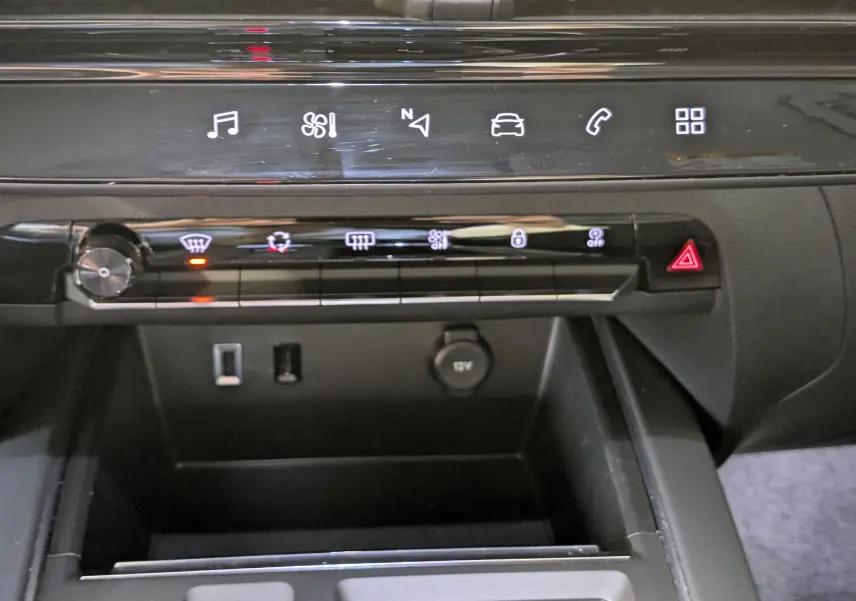 Vue rapprochée de la console centrale noire du Citroën C5 Aircross 2024 avec commandes tactiles et prise 12V visible.