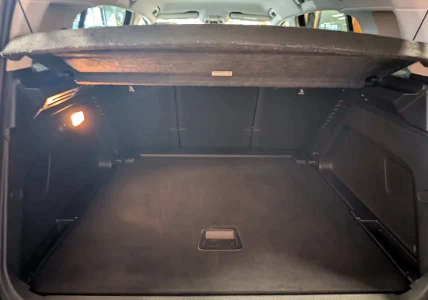 Coffre ouvert vu de l'arrière d'un Citroën C5 Aircross noir 2024, espace de chargement avec éclairage intérieur.