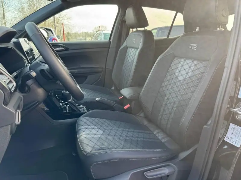 Intérieur du Volkswagen T-Cross 2025 noir nacré, vue côté conducteur sur sièges R-Line avec surpiqûres et volant.