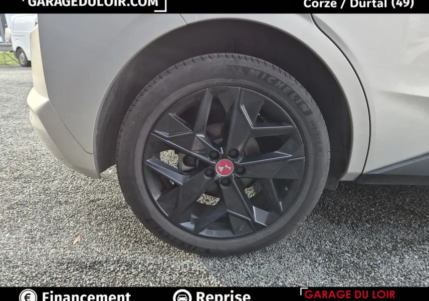 Gros plan sur la roue arrière droite noire au design géométrique du DS4 beige 2024 BlueHDi Performance Line.