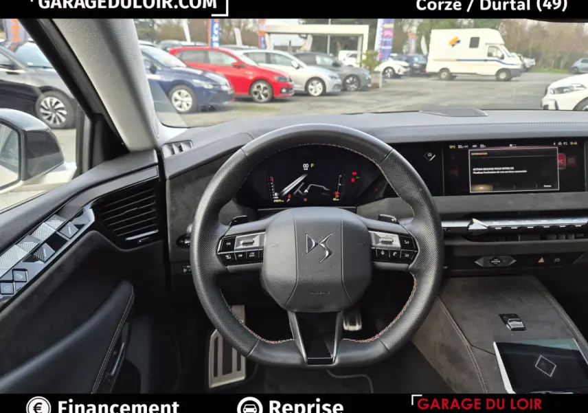 Vue intérieure centrée sur le volant cuir DS d'une DS4 beige, avec tableau de bord digital et écran tactile large.