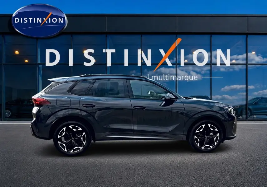Vue latérale droite du SUV CUPRA Terramar gris Timanfaya avec jantes alu noires et toit noir, devant une vitrine Distinxion.