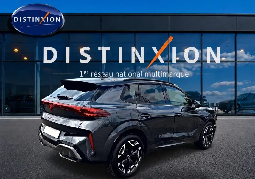 Vue 3/4 arrière droite d'un SUV CUPRA Terramar gris Timanfaya avec jantes 19 pouces et feux arrière LED allumés.