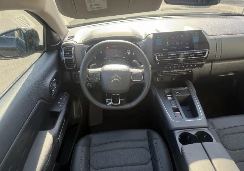 Vue intérieure avant du Citroën C5 Aircross 2025, tableau de bord et volant noirs avec écran tactile central.