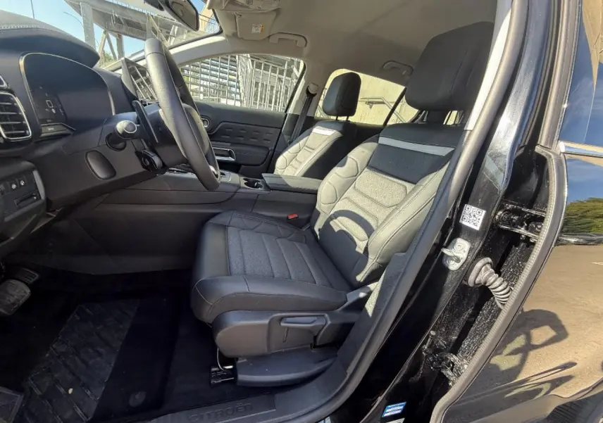 Vue intérieure côté conducteur du Citroën C5 Aircross 2025 avec sièges en tissu et cuir noir, tableau de bord moderne.