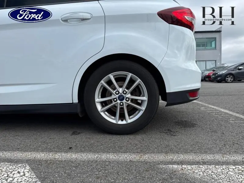 Vue latérale côté gauche sur l'arrière d'un Ford C-MAX blanc Glacier, mettant en valeur la roue alu et le feu arrière.