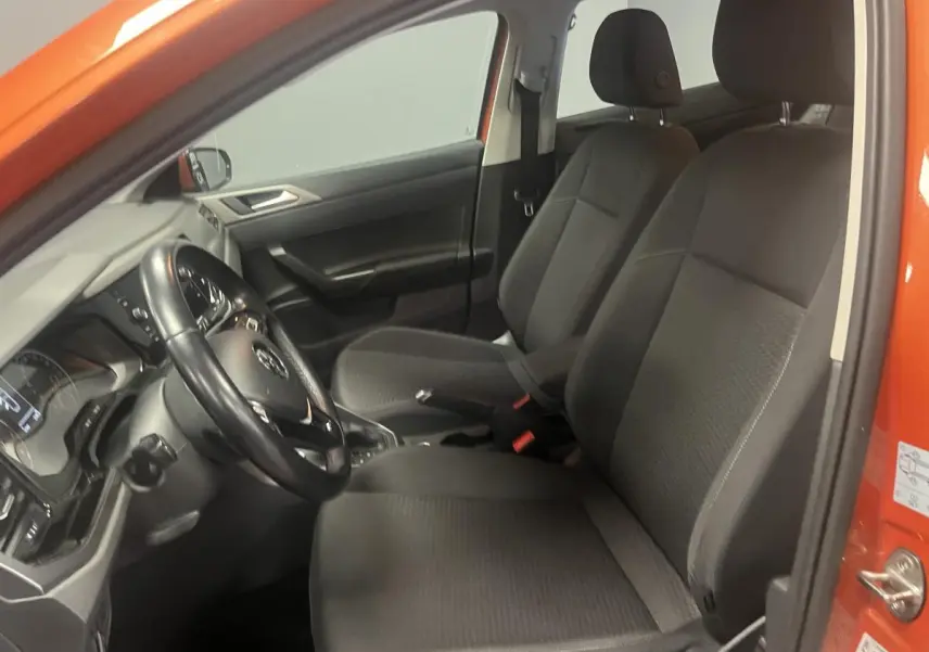 Intérieur côté conducteur d'une Volkswagen Polo orange 2019 avec sièges tissu noirs et volant cuir multifonction.