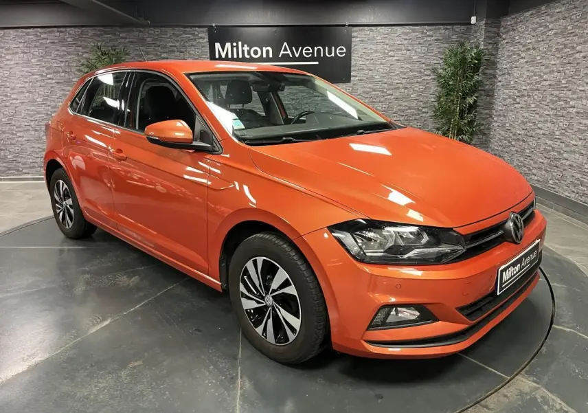 Volkswagen Polo orange vue 3/4 avant droit, jantes alliage bicolores et calandre avec logo VW visible