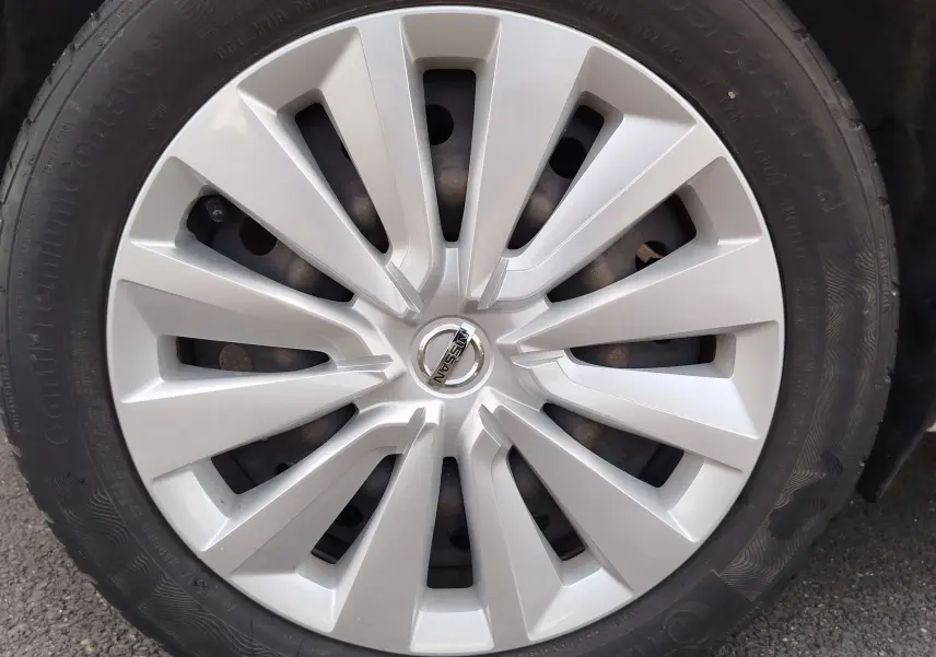 Gros plan sur la jante argentée d'une Nissan Micra blanche de 2019, avec logo Nissan au centre.