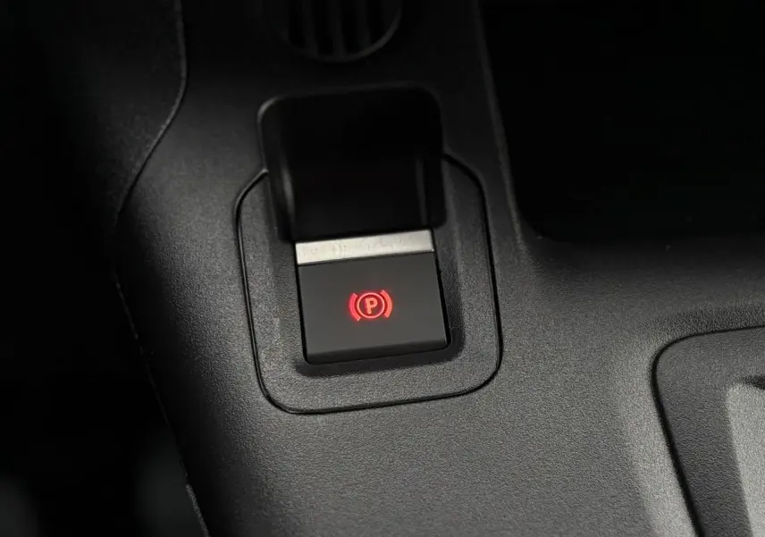 Gros plan sur le bouton de frein de stationnement électrique rouge dans l'habitacle du Citroën Berlingo blanc Icy 2025.