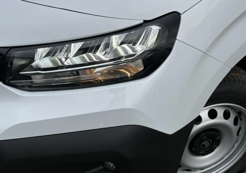 Gros plan sur le phare avant droit et la roue tôle grise du Citroën Berlingo blanc Icy 2025.