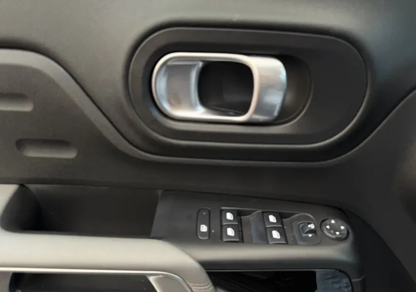 Poignée de porte intérieure et commandes des vitres côté conducteur du Citroën C5 Aircross gris clair, vue rapprochée.