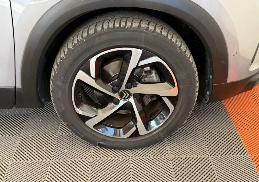 Gros plan sur la roue avant droite gris clair du Citroën C5 Aircross avec jante alliage noire et argentée.