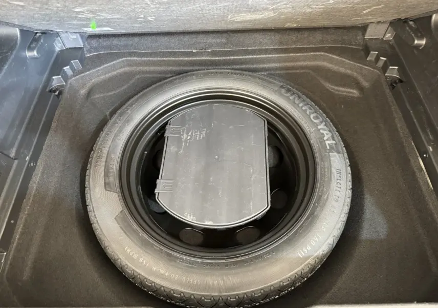 Vue plongeante sur la roue de secours Uniroyal dans le coffre noir du Citroën C5 Aircross gris clair 2020.