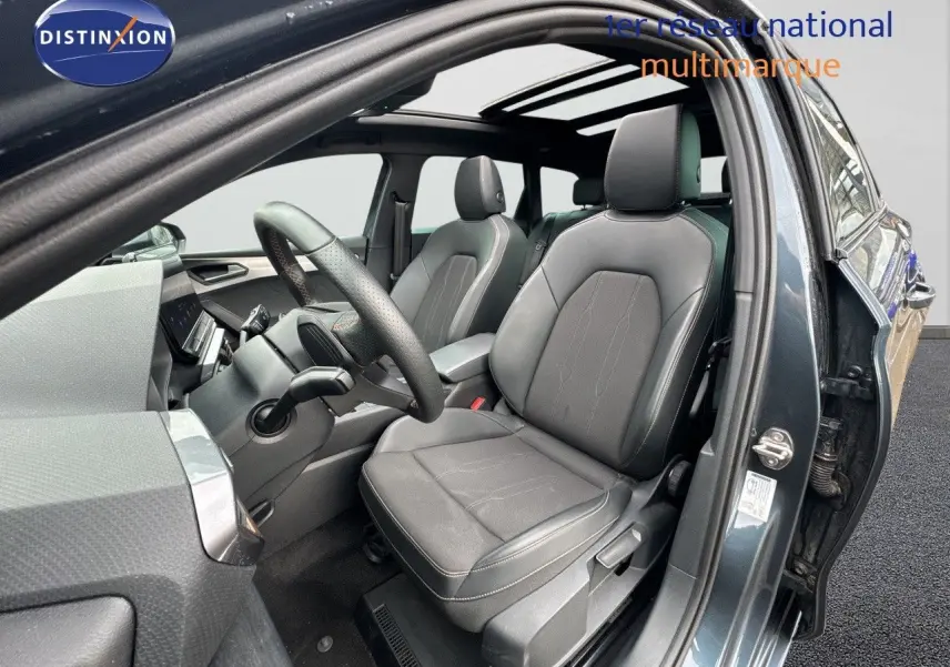 Vue intérieure côté conducteur de la CUPRA LEON ST 1.5 gris Magnetic Metal avec sièges en cuir noir et toit panoramique.