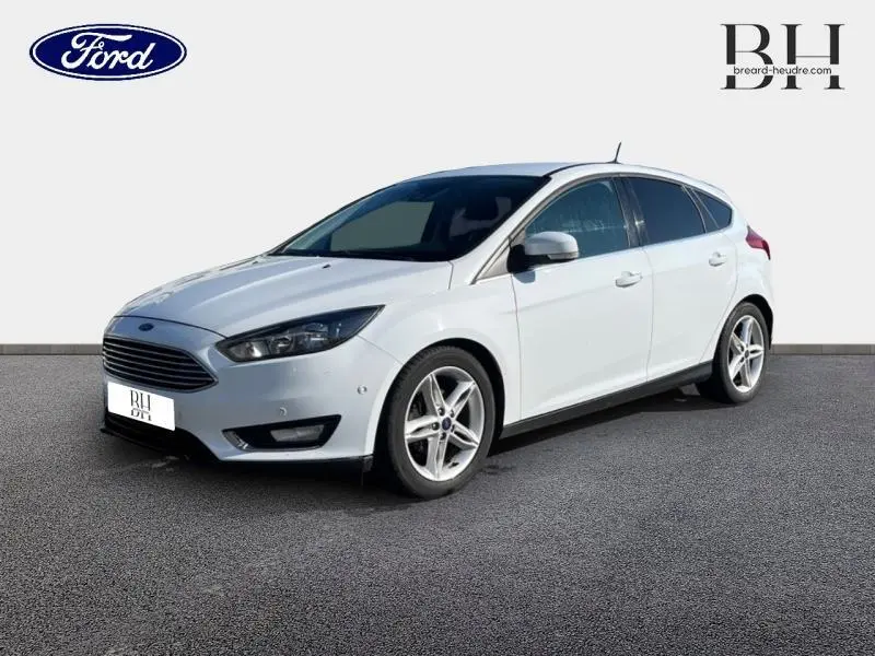 Ford Focus blanc glacier vue 3/4 avant droit, avec calandre chromée et jantes alliage cinq branches.