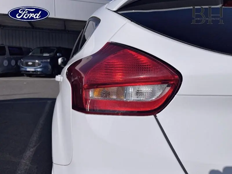 Gros plan sur le feu arrière droit d'une Ford Focus blanc glacier, soulignant la finition lisse et les lignes du coffre.