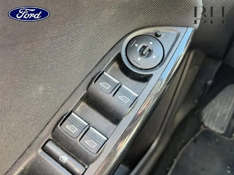 Gros plan sur les commandes de lève-vitres et réglage des rétroviseurs côté conducteur d'une Ford Focus 2017.