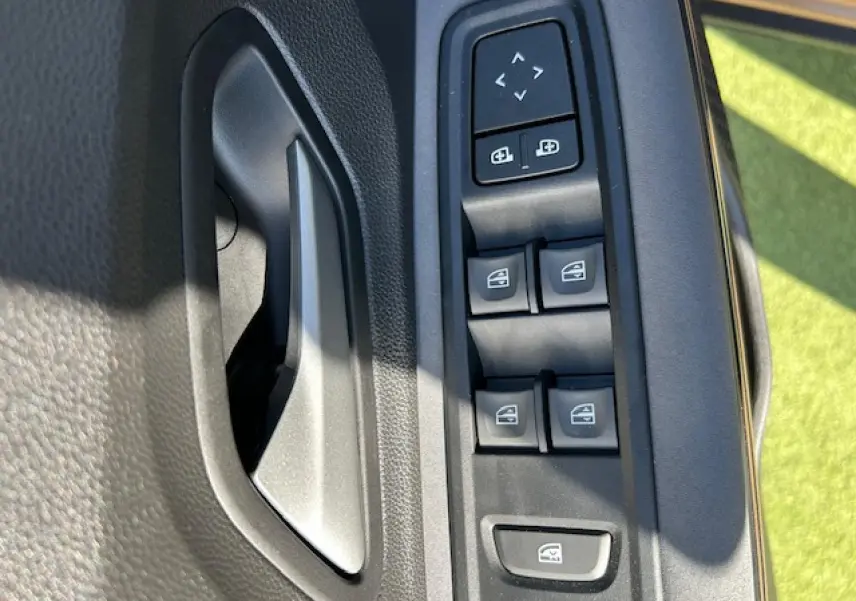 Gros plan sur la commande des vitres électriques et des rétroviseurs côté conducteur de la Dacia Sandero III Stepway beige Safari.