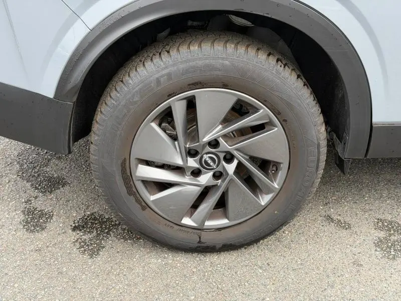 Gros plan sur la roue avant gauche du Nissan Qashqai 2025 gris Argile avec jante alu au design moderne.