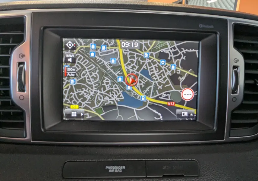 Écran de navigation GPS intégré au tableau de bord d’un Kia Sportage gris, vue frontale rapprochée.
