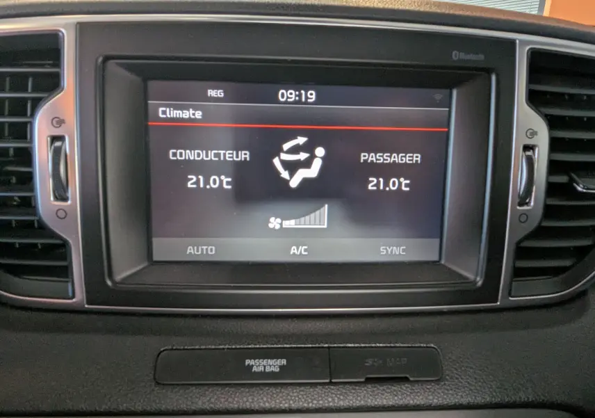 Écran central du tableau de bord du Kia Sportage 2016 affichant la climatisation bi-zone à 21°C pour conducteur et passager.