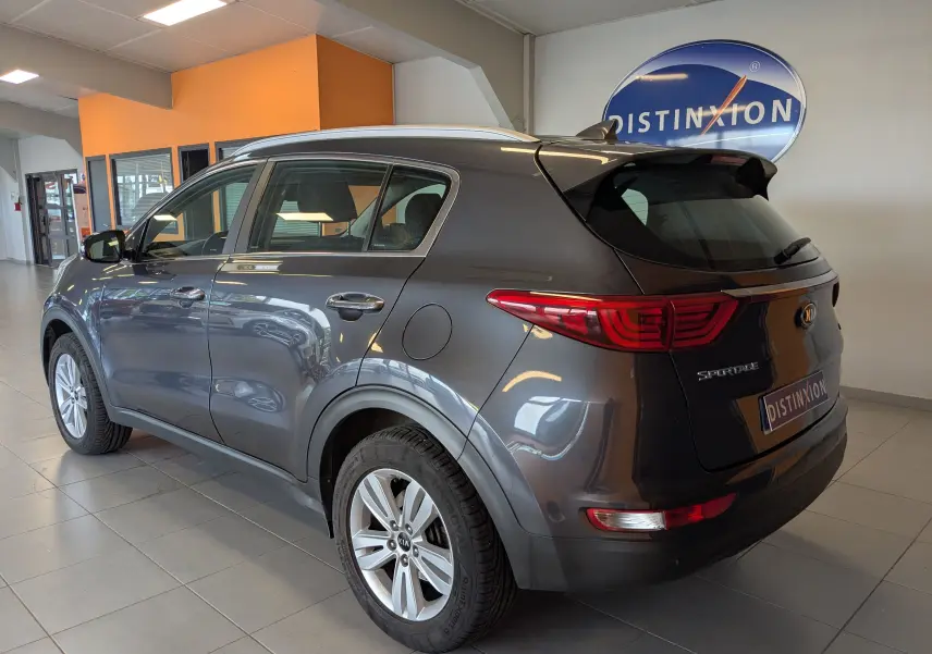 Vue 3/4 arrière droite du KIA Sportage gris 2016 en intérieur, avec feux arrière allongés et jantes alliage.