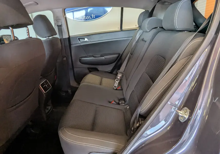 Vue intérieure côté droit des sièges arrière gris foncé du Kia Sportage 2016 avec ceinture de sécurité et appuie-têtes visibles.