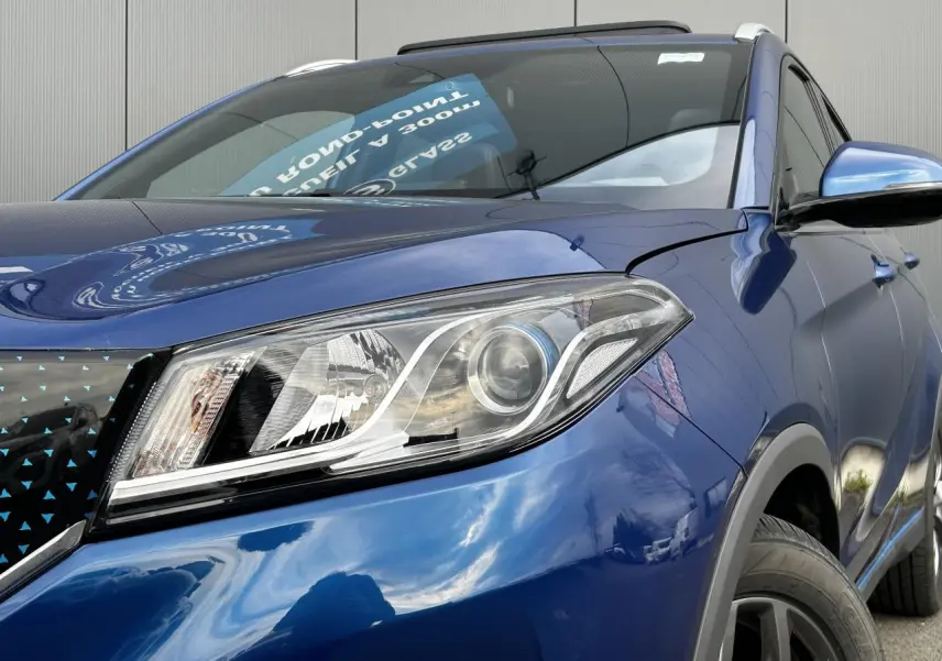 Gros plan sur le phare avant droit bleu du SUV électrique SERES 3 163 Luxury avec calandre noire à motifs bleus.