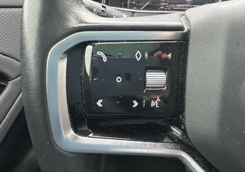 Gros plan sur les commandes multifonctions noires à gauche du volant du Range Rover Evoque gris foncé 2022.