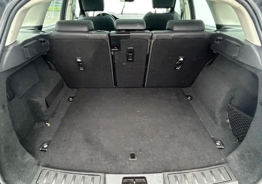 Coffre spacieux du Range Rover Evoque gris foncé, vue arrière avec sièges arrière relevés et habillage intérieur noir.