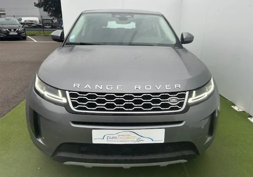 Vue de face d'un Range Rover Evoque gris foncé métallisé avec calandre hexagonale et phares LED allumés.