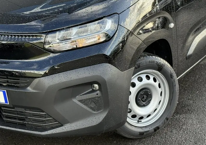 Gros plan sur l'avant droit noir perla du Citroën Berlingo Van 2025 avec phare et jante tôle grise visible sous la pluie.