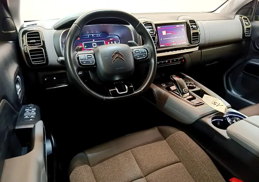 Intérieur du Citroën C5 Aircross 2020, vue côté conducteur, volant cuir noir et tableau de bord digital lumineux.