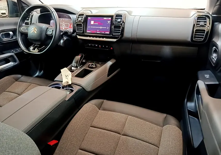 Intérieur du Citroën C5 Aircross 2020 avec tableau de bord noir et beige, volant cuir multifonctions et écran tactile central.