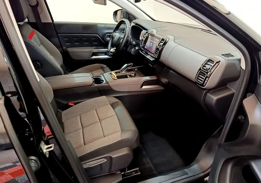 Intérieur côté conducteur du Citroën C5 Aircross noir, avec sièges tissu gris et tableau de bord moderne équipé d’un écran tactile.