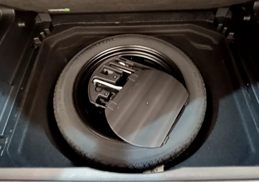 Gros plan sur la roue de secours et son rangement dans le coffre du Citroën C5 Aircross noir de 2020.