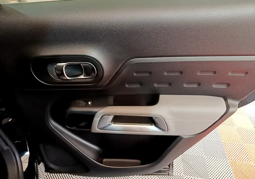 Gros plan sur la porte intérieure côté gauche du Citroën C5 Aircross noir, avec poignée argentée et garniture texturée.